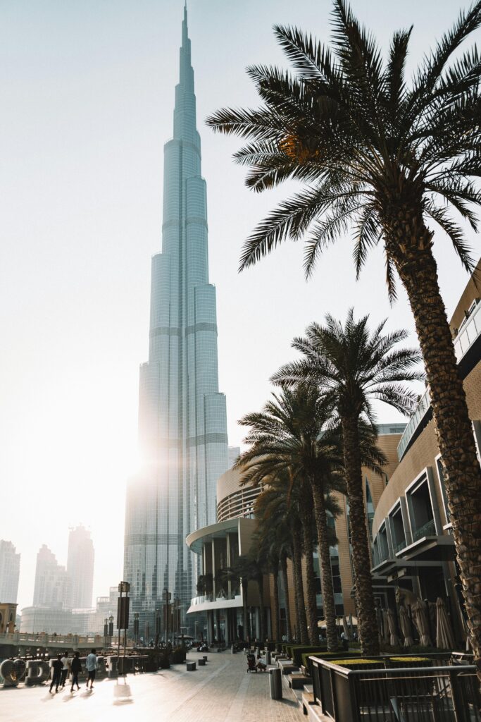 Sunlit view of Burj Khalifa surrounded by palm trees and modern architecture in Dubai.